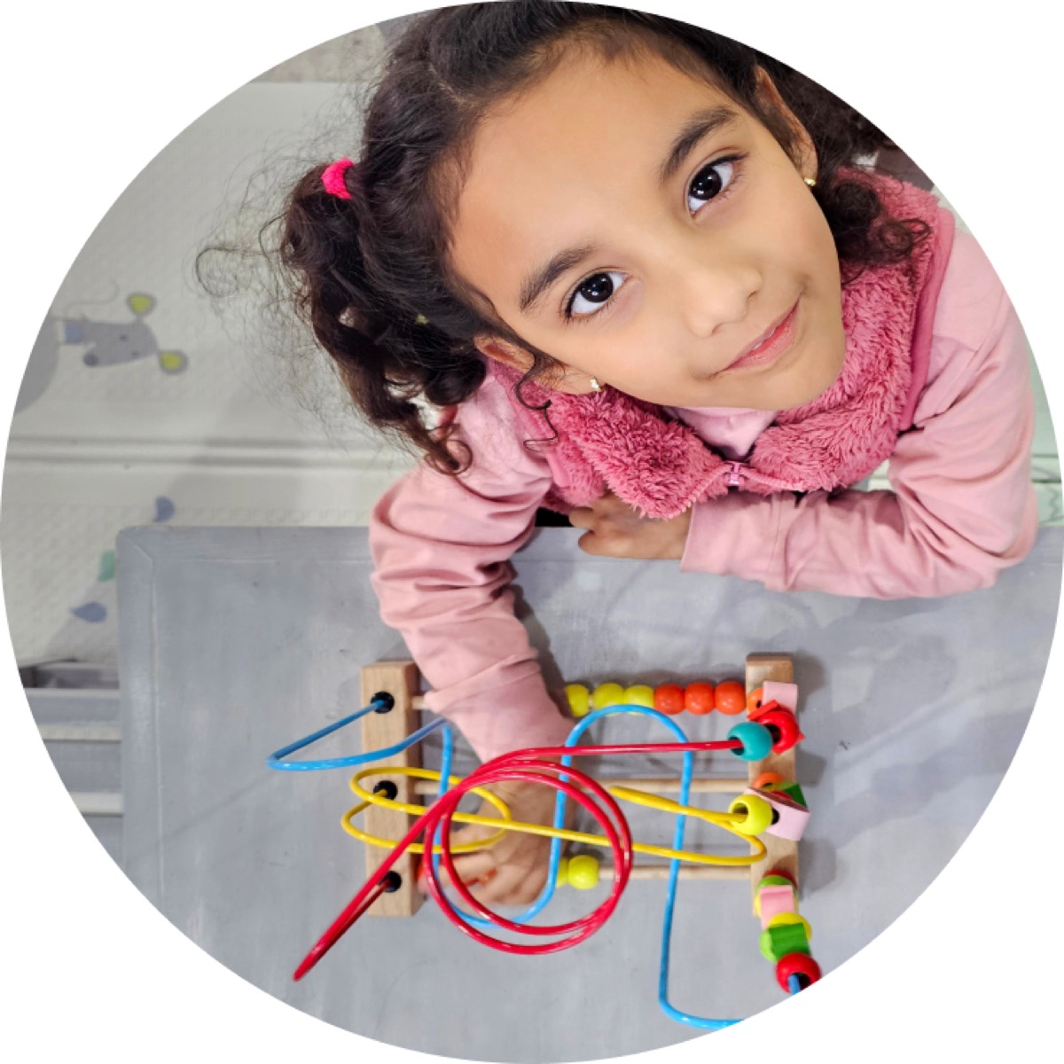 A young girl smiling over a bead maze toy
