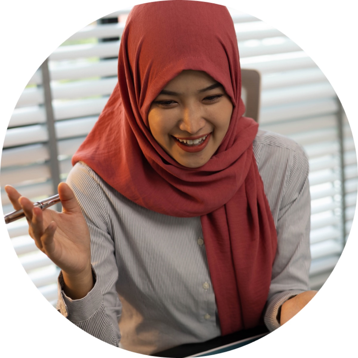 A woman in a hijab talking and gesturing at her desk