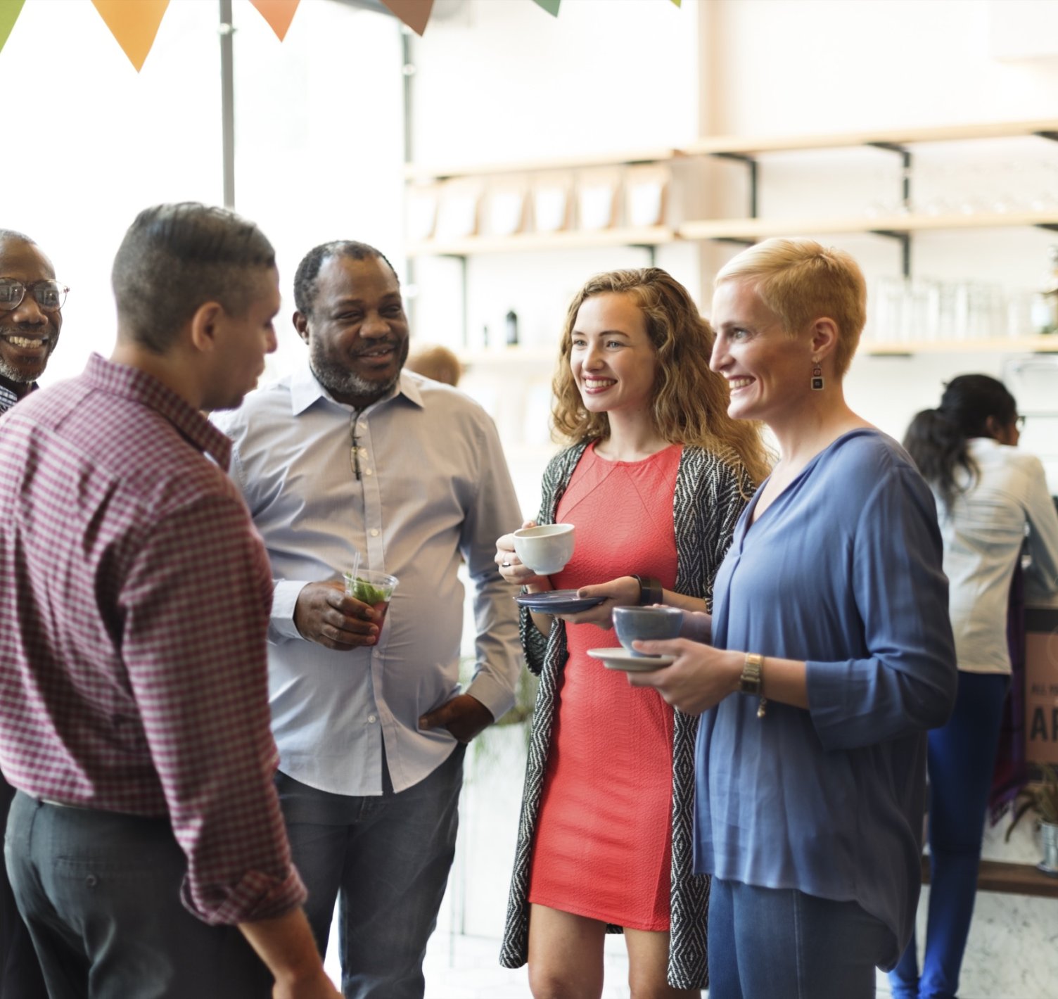Three adults chatting and smiling over drinks at a social gathering